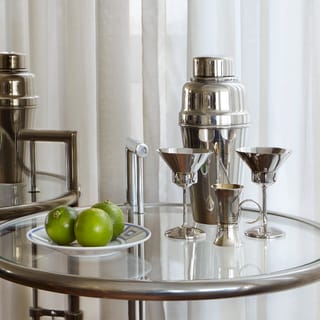A chic drinks table with a silver cocktail shaker and silver glasses