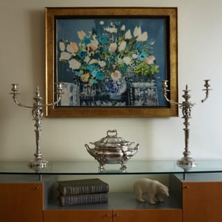 A silver soup tureen and pair of silver candelabra on a sideboard